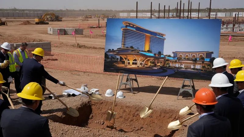 Construction workers in hard hats hold golden shovels at a groundbreaking ceremony.